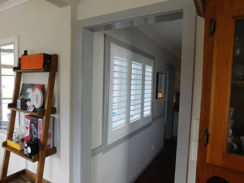 White plantation shutters seen down a hallway, through an open doorway — one of our own jobs