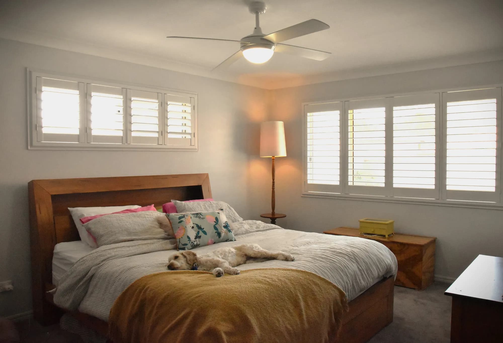 White plantation shutters on a main bedroom's windows and highlight windows — one of our own jobs