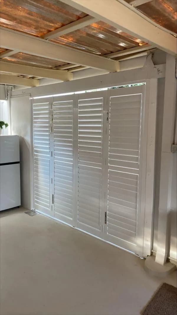 A wall of shutter doors closed across an outdoor room — one of our own jobs