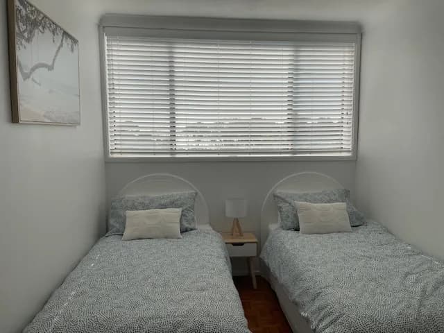 A white venetian blind above two single beds in a children's bedroom — one of our own jobs