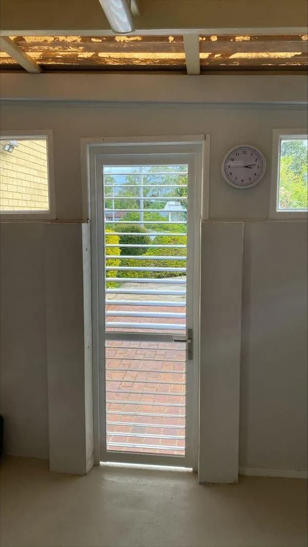 A shutter panel fitted to a glass door, with matching highlight windows — one of our own jobs