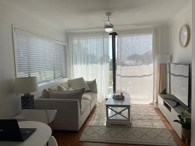 A white venetian blind in a lounge room, sheer curtains on the door beside it — one of our own jobs